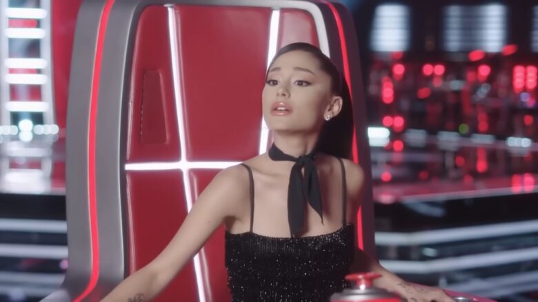 Singer in a black outfit seated in a red TV show chair