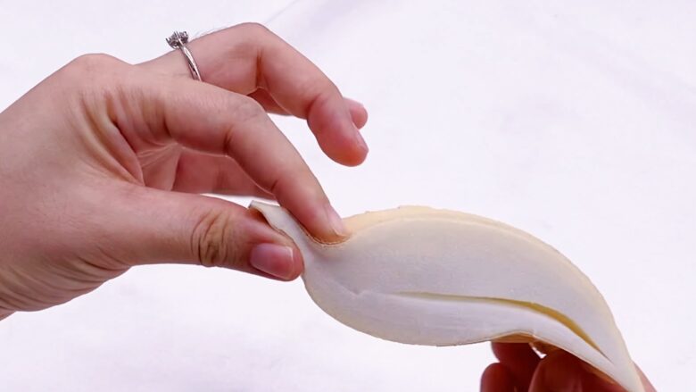 Hand holding an adhesive bra cup against a plain light background