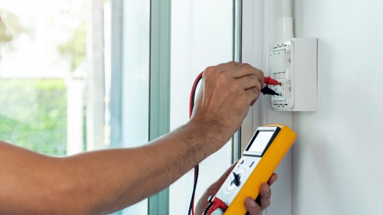 A hand tests a home outlet with a multimeter
