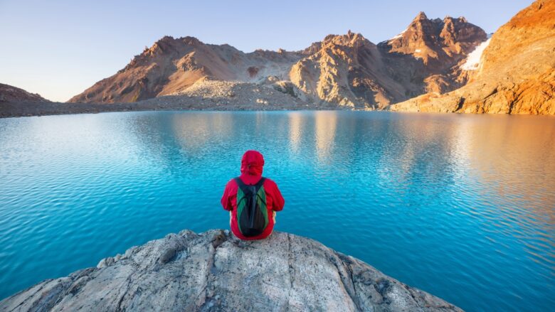 Traveler sits beside a blue mountain lake in South America