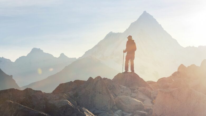 Hiker stands on a rocky mountain ridge at sunrise