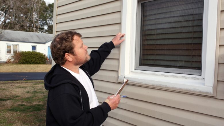 A home inspector checks an exterior window frame