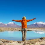 Traveler facing a blue lagoon and snow-capped mountains in South America