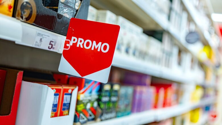 Red promo sign hangs on a store shelf with products in the background