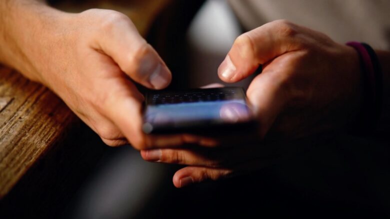 A person uses a smartphone with both hands at a table