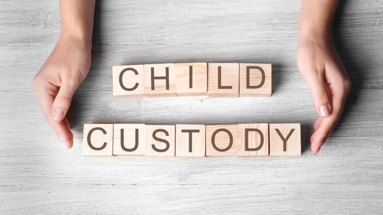Hands protect wooden blocks that spell child custody