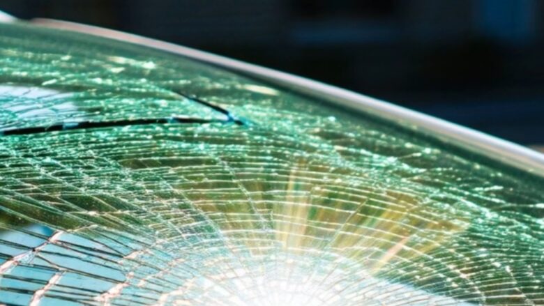A cracked car windshield reflects bright sun in extreme heat