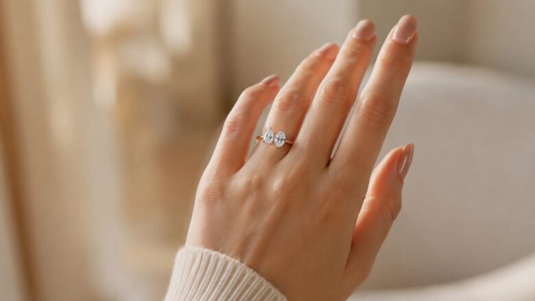 A woman wears a gold Toi et Moi engagement ring with oval and pear-shaped diamonds