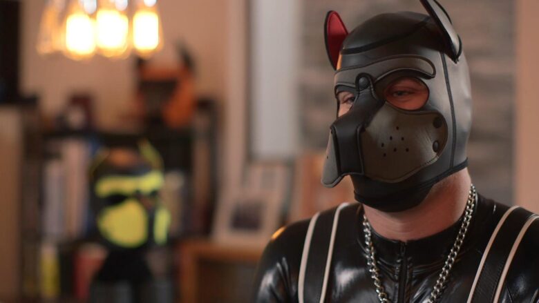 Adult wearing a puppy play mask and black role-play outfit.