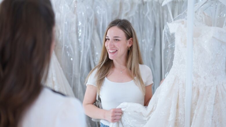 Bride looks at lace wedding dresses with a bridal consultant