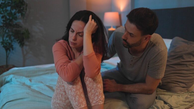 A worried woman sits beside her partner during a tense conversation.