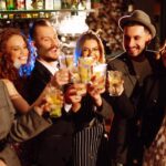 Friends raise cocktails together at a lively bar at night.