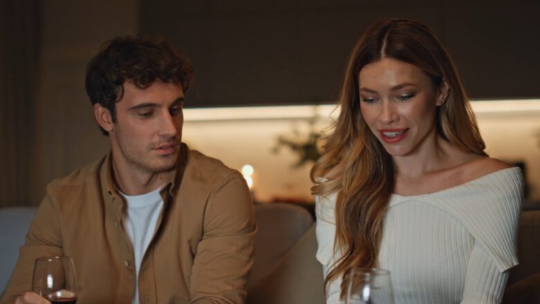 A man and woman talk over glasses of wine at home.