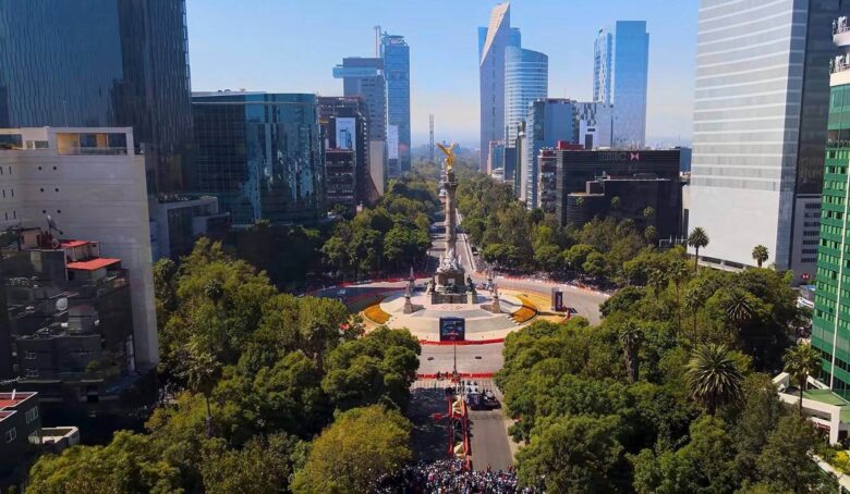Aerial view of the Angel of Independence monument surrounded by skyscrapers and trees in Mexico City.