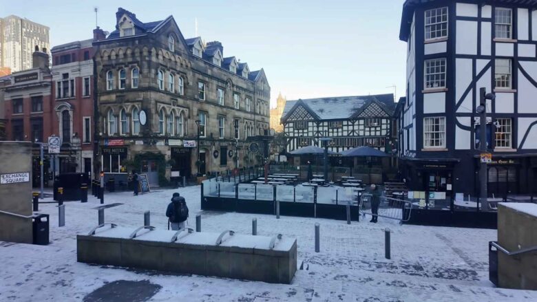 Snow-covered Exchange Square in Manchester with historic buildings