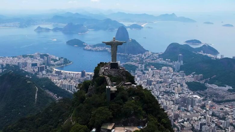 Christ the Redeemer statue above Rio de Janeiro with Sugarloaf Mountain and the bay in the distance.