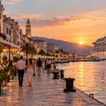 Cruise ship docked beside a lively waterfront city at sunset