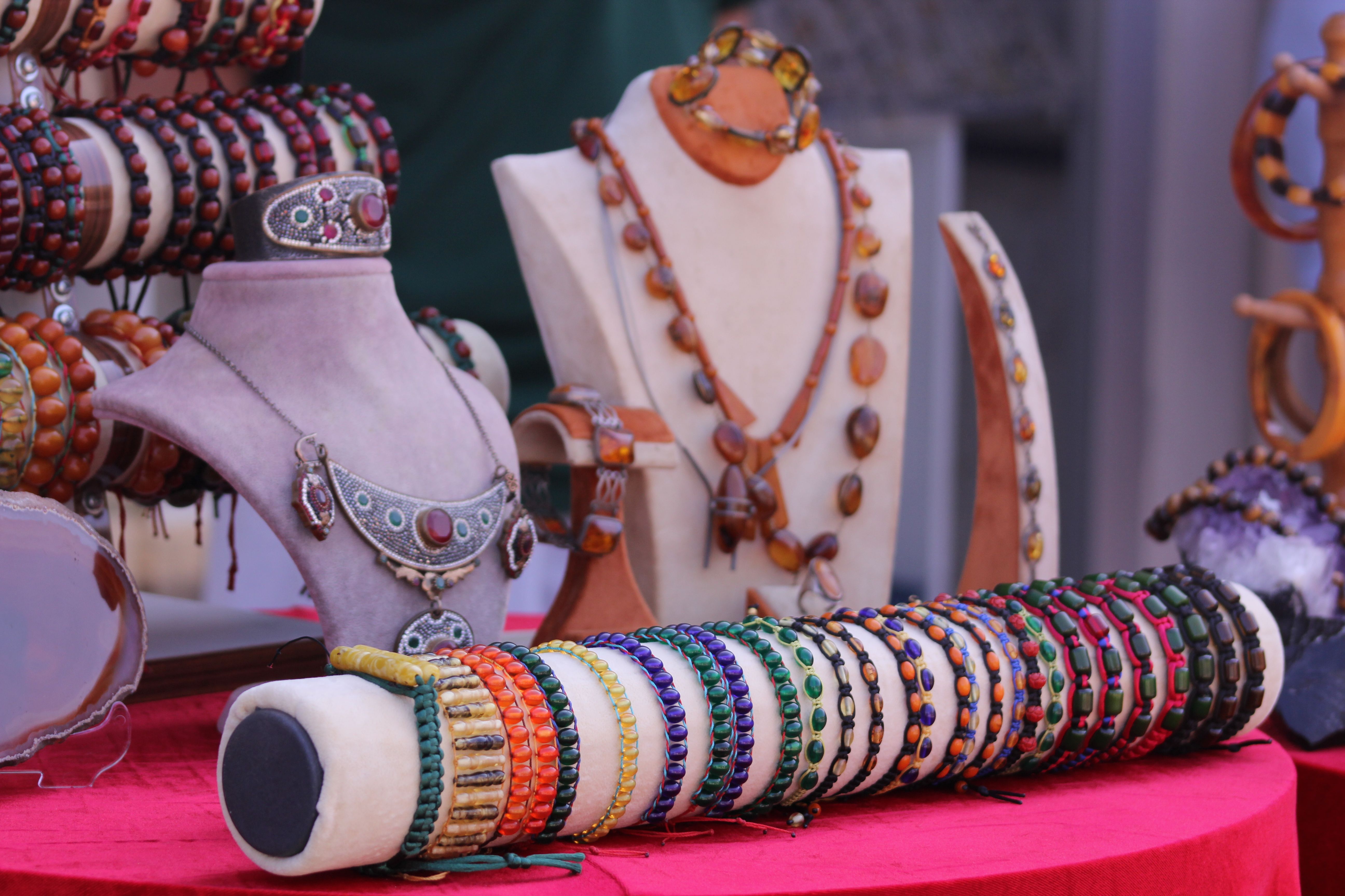 Colorful handcrafted bracelets and necklaces arranged on display stands.