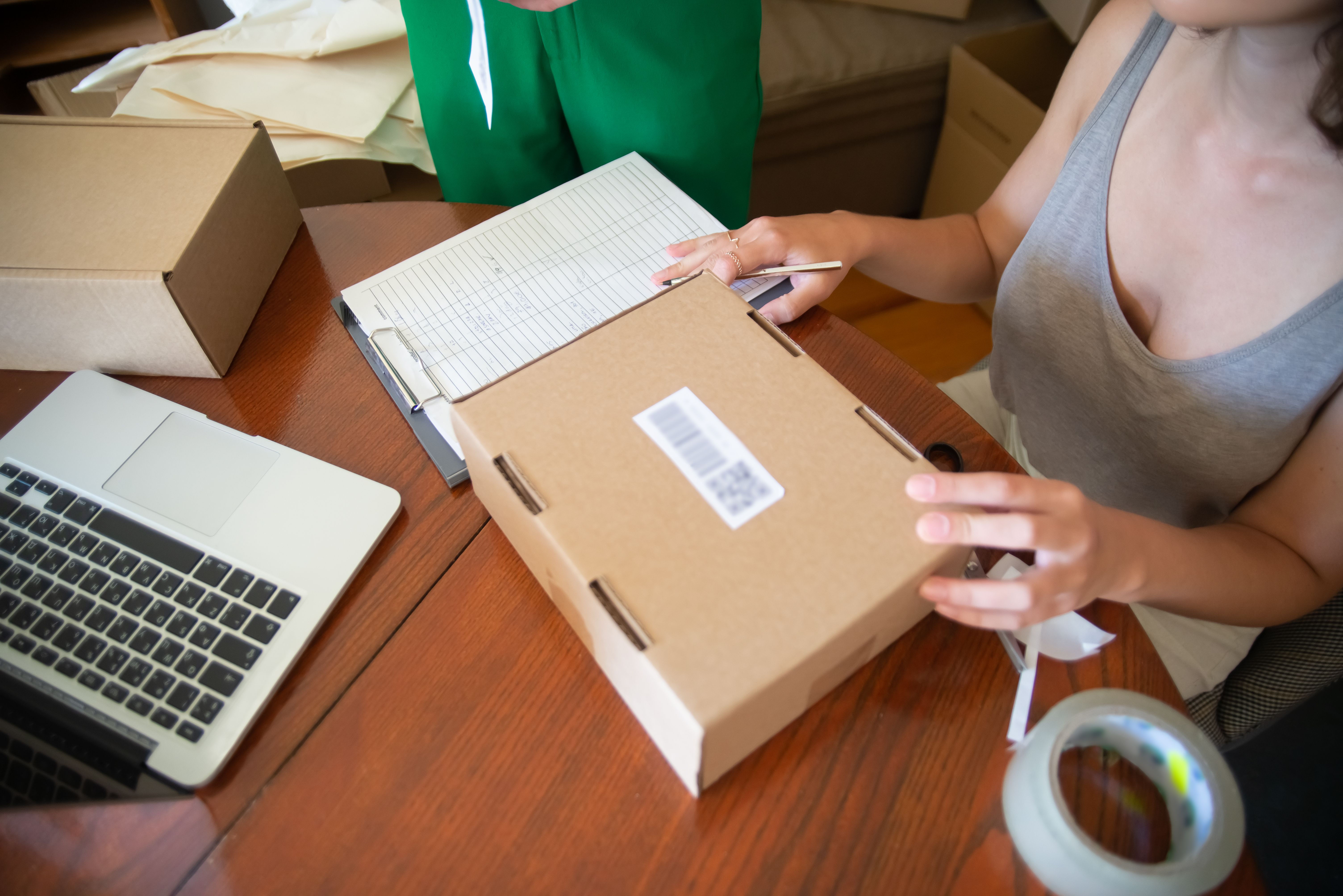 Small-business owners packing online customer orders beside a laptop.